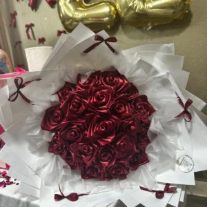 Burgundy satin rose bouquet with white layered wrapping and burgundy ribbon bows, close-up view